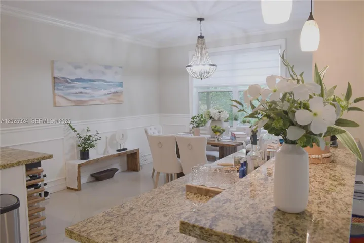 Bright and elegant dining space featuring a refined chandelier, custom wainscoting, and a serene accent wall—perfect for intimate meals and gatherings.