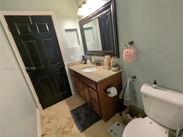 Second bathroom featuring a granite-top vanity, updated lighting, and a clean, well-maintained layout that provides comfort and functionality for daily use.