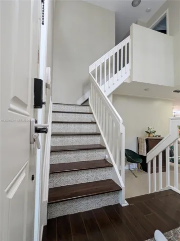 Inviting entry area featuring a modern staircase with patterned risers, wood steps, and clean white railings, creating a stylish transition between levels.