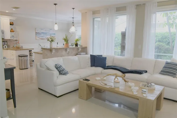 Open integrated living and kitchen layout featuring a bright seating area, coastal décor accents, and a well-connected space ideal for everyday living and entertaining.