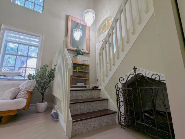 Charming staircase landing featuring decorative risers, accent wall, gorgeous chandelier, and warm natural light that enhances the home’s inviting character.