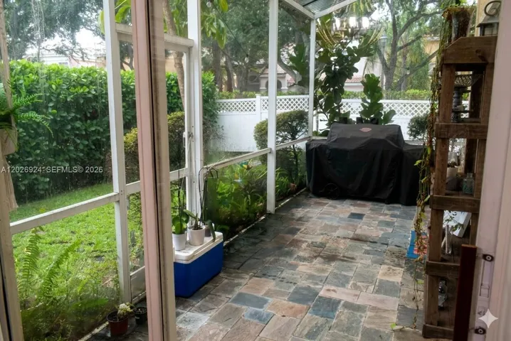 Lush landscape view from the screened-in patio. Stone tile flooring, and room for a covered grill area, offering a comfortable outdoor space protected from the elements.
