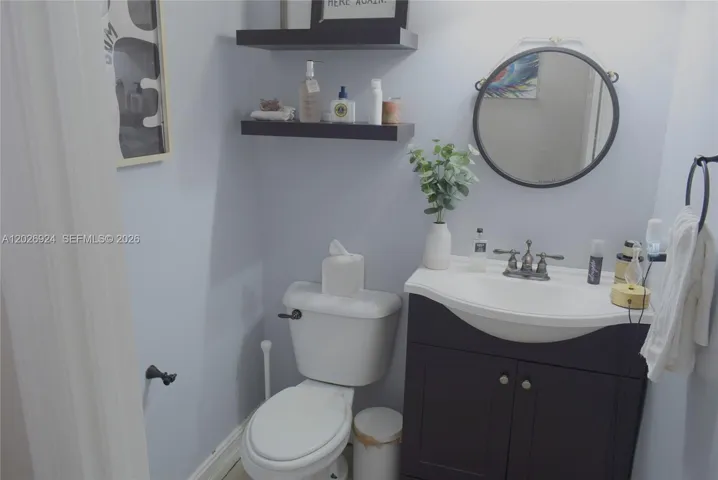 Clean and well-appointed guest bathroom featuring modern fixtures, floating shelving, and a neatly organized vanity area.