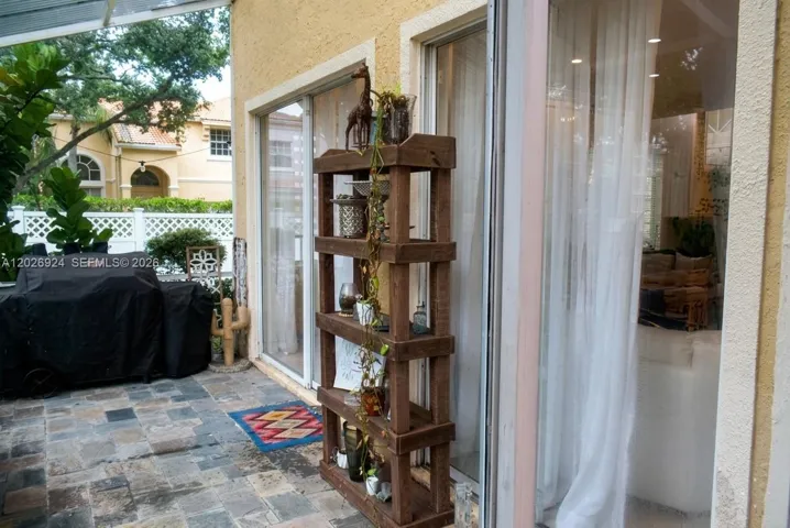 Cozy outdoor screened patio featuring stone flooring, sliding glass doors, offering a comfortable space for relaxing or entertaining.