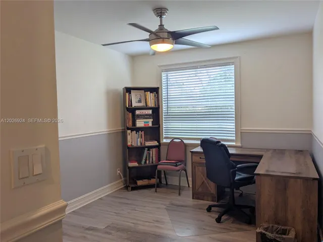 Third bedroom currently set up as a home office, featuring wood-style flooring, closet, natural light, and a ceiling fan, offering a versatile space for work or living.