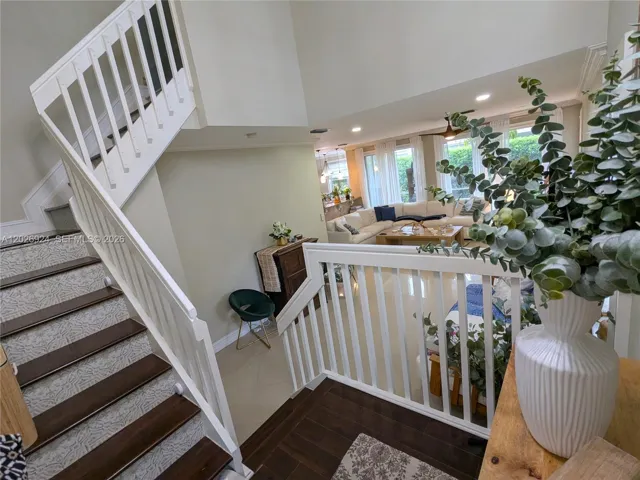 Beautiful transition foyer space showcasing a stylish staircase, warm natural textures, and an open living area filled with light and inviting décor.