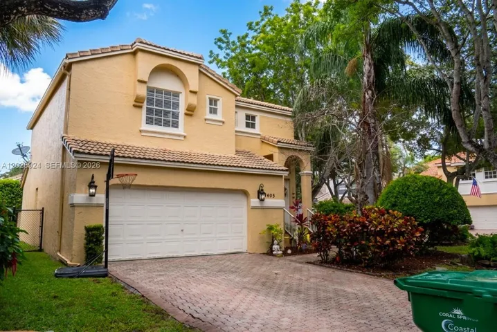 Beautiful 3-bed, 2.5-bath home featuring a spacious brick-paved driveway, tropical landscaping, and elegant Mediterranean architectural details.
