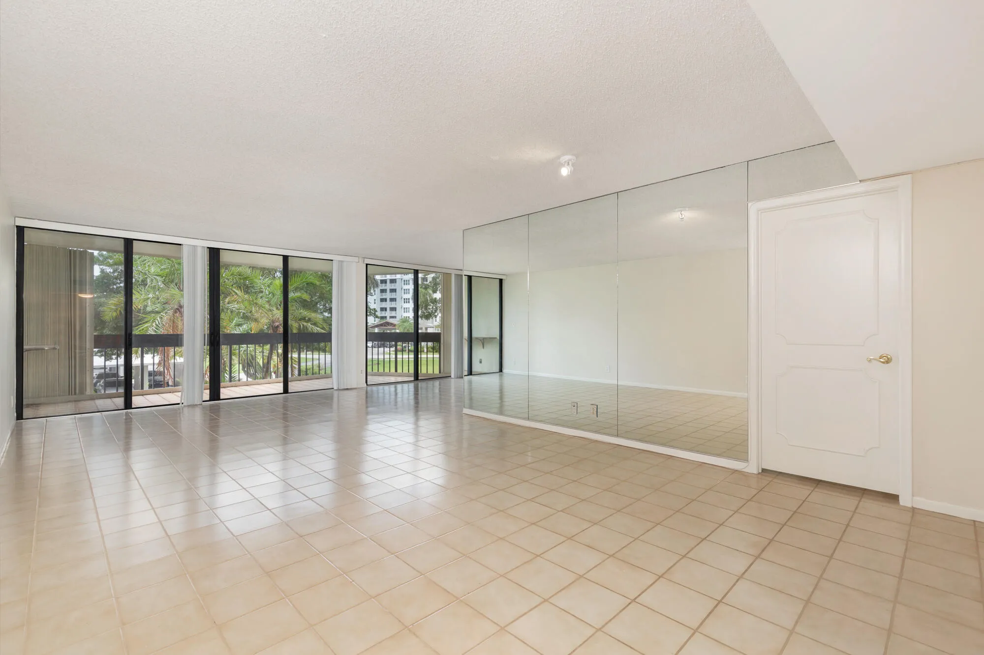 Large living Room with balcony of palm tree top views facing south west. Unit on second floor.
