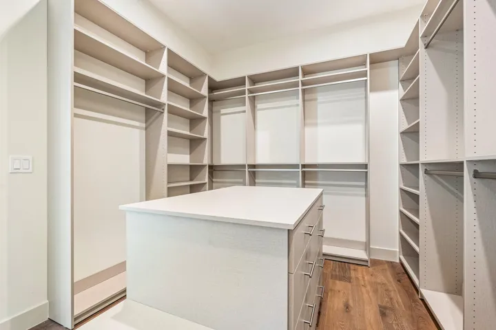 Experience effortless organization in the custom-built closet, featuring a signature island with dedicated jewelry storage, complemented by extensive shelving and refined hanging areas