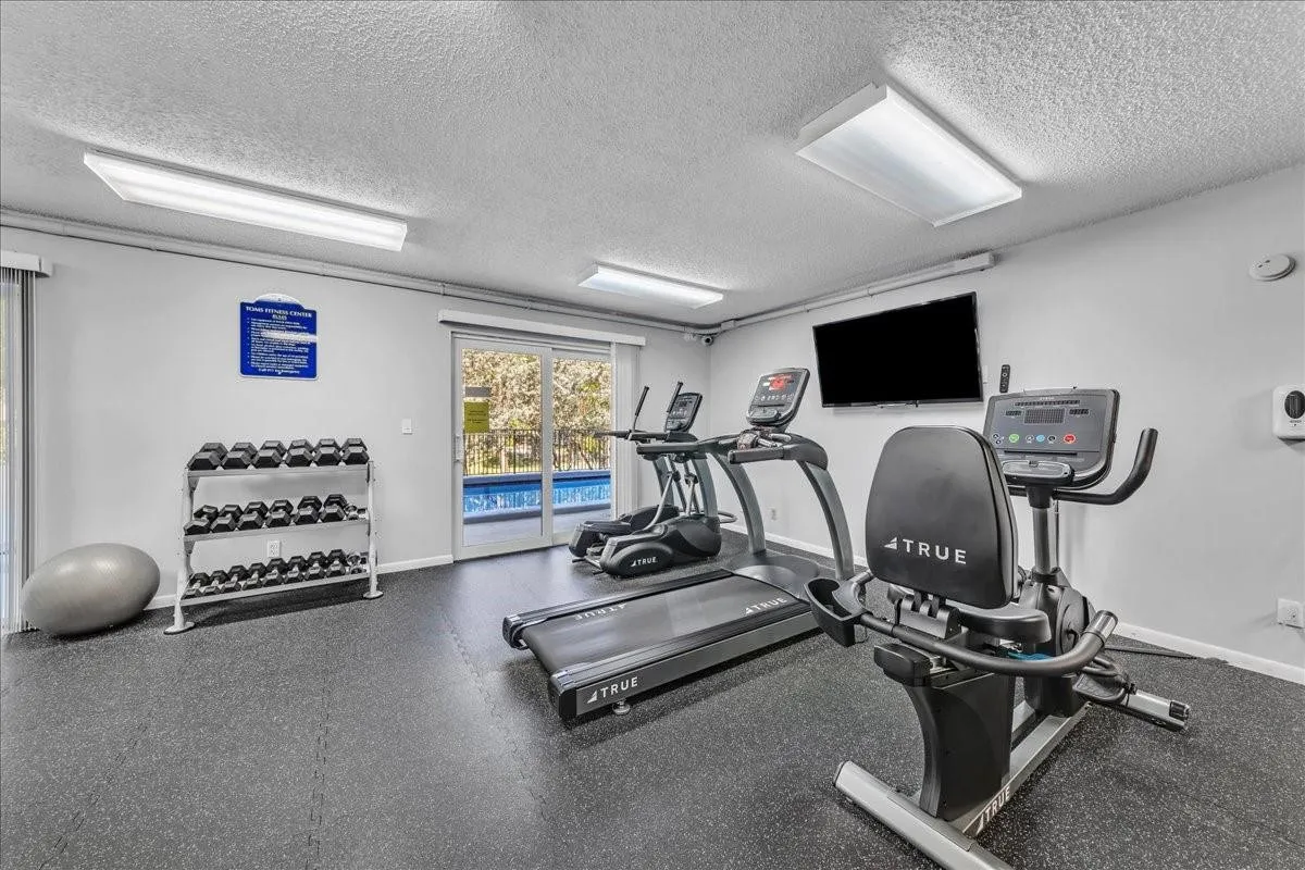 Modern fitness center with treadmills and cardio equipment overlooking the pool in Fort Lauderdale condo.
