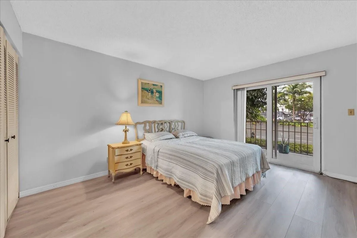 Bedroom with sliding glass doors to private balcony and tropical view in Fort Lauderdale condo.