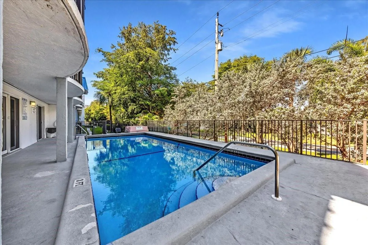 Sparkling blue pool surrounded by tropical landscaping and sun loungers at Top of the Mile condos in Fort Lauderdale.
