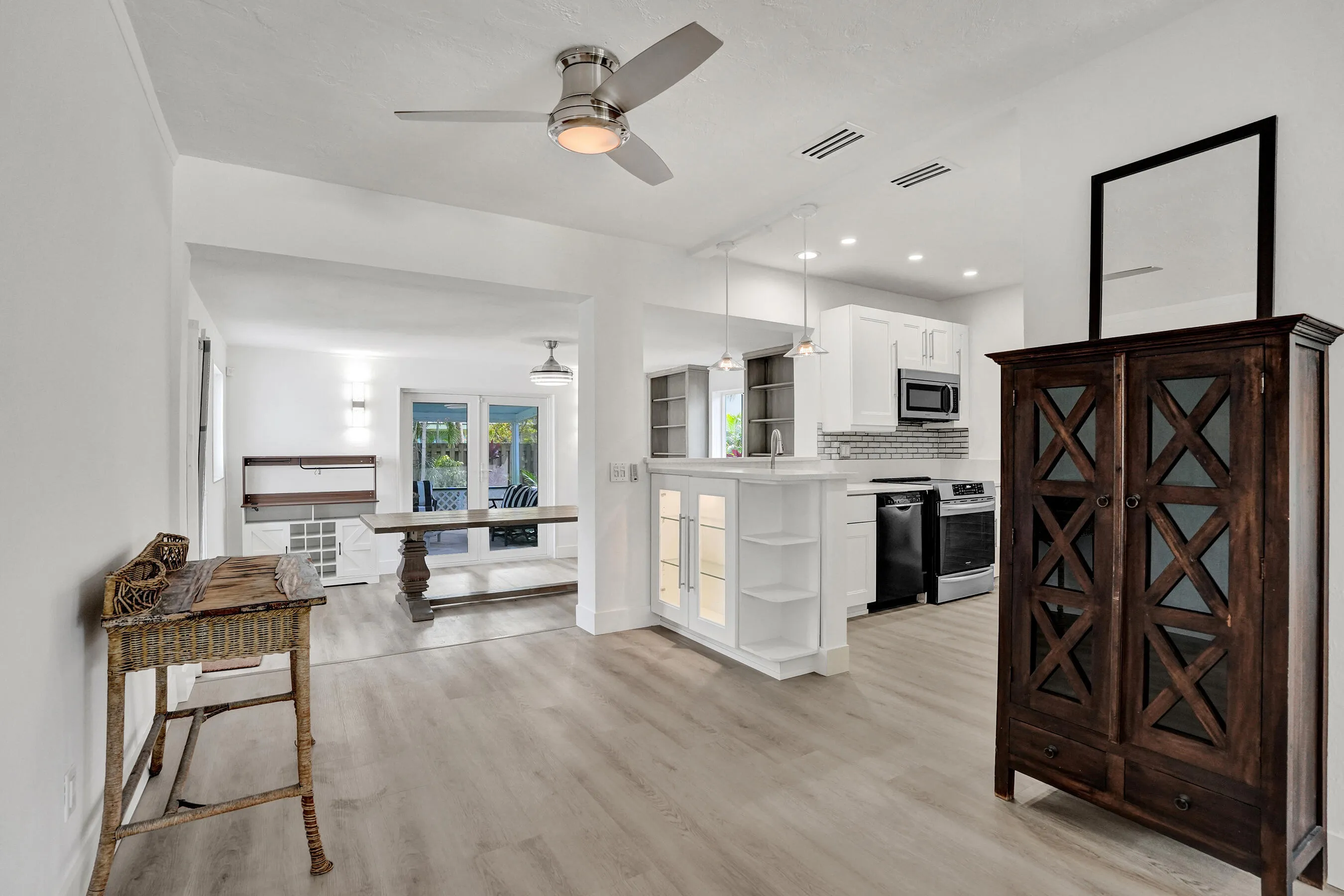 Open space with kitchen, dining and screened patio in the background