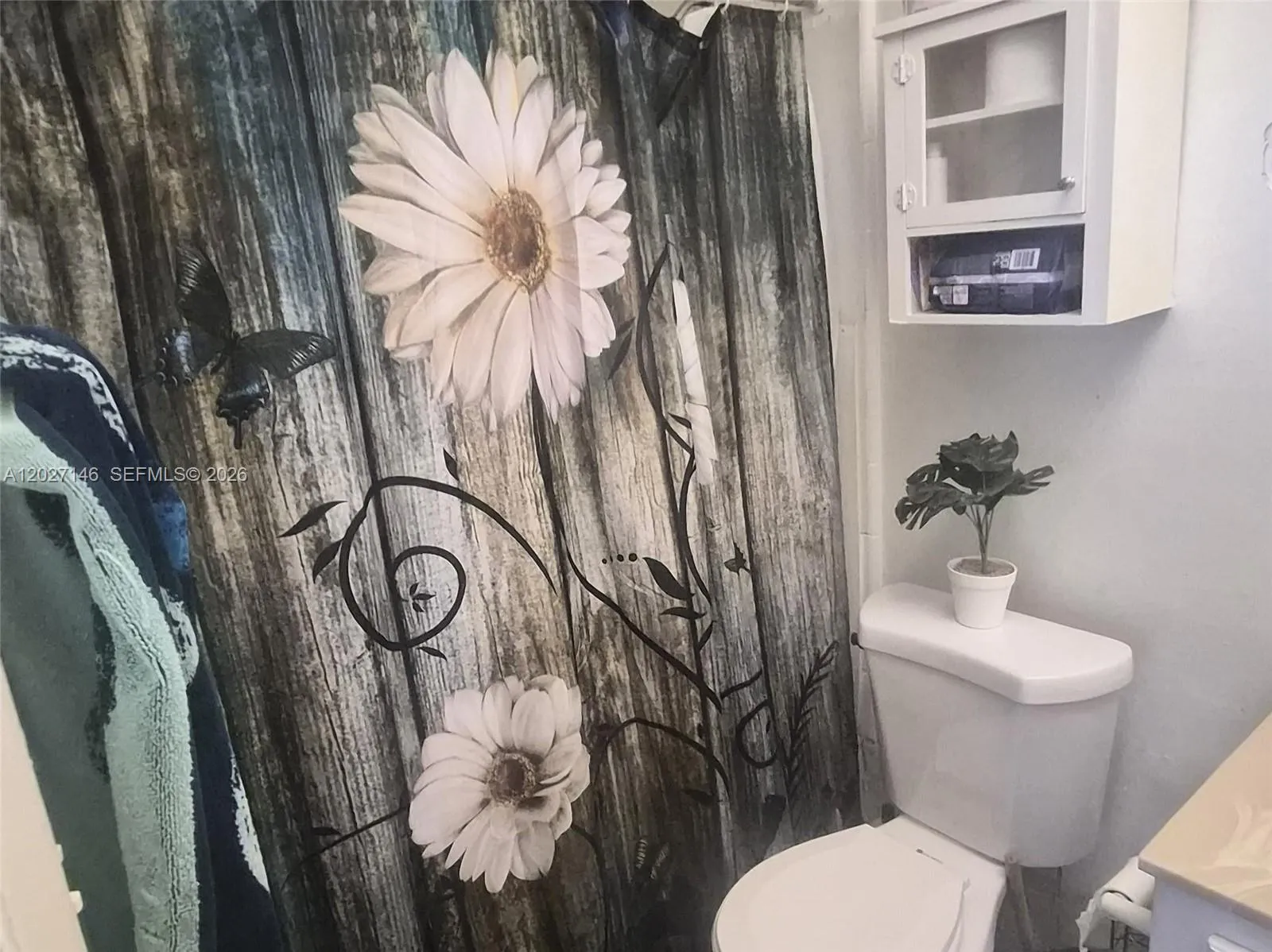 Full bathroom complete with a clean white vanity, large mirror, drop-ceiling tile design, and a full-size bathtub paired with a decorative shower curtain.