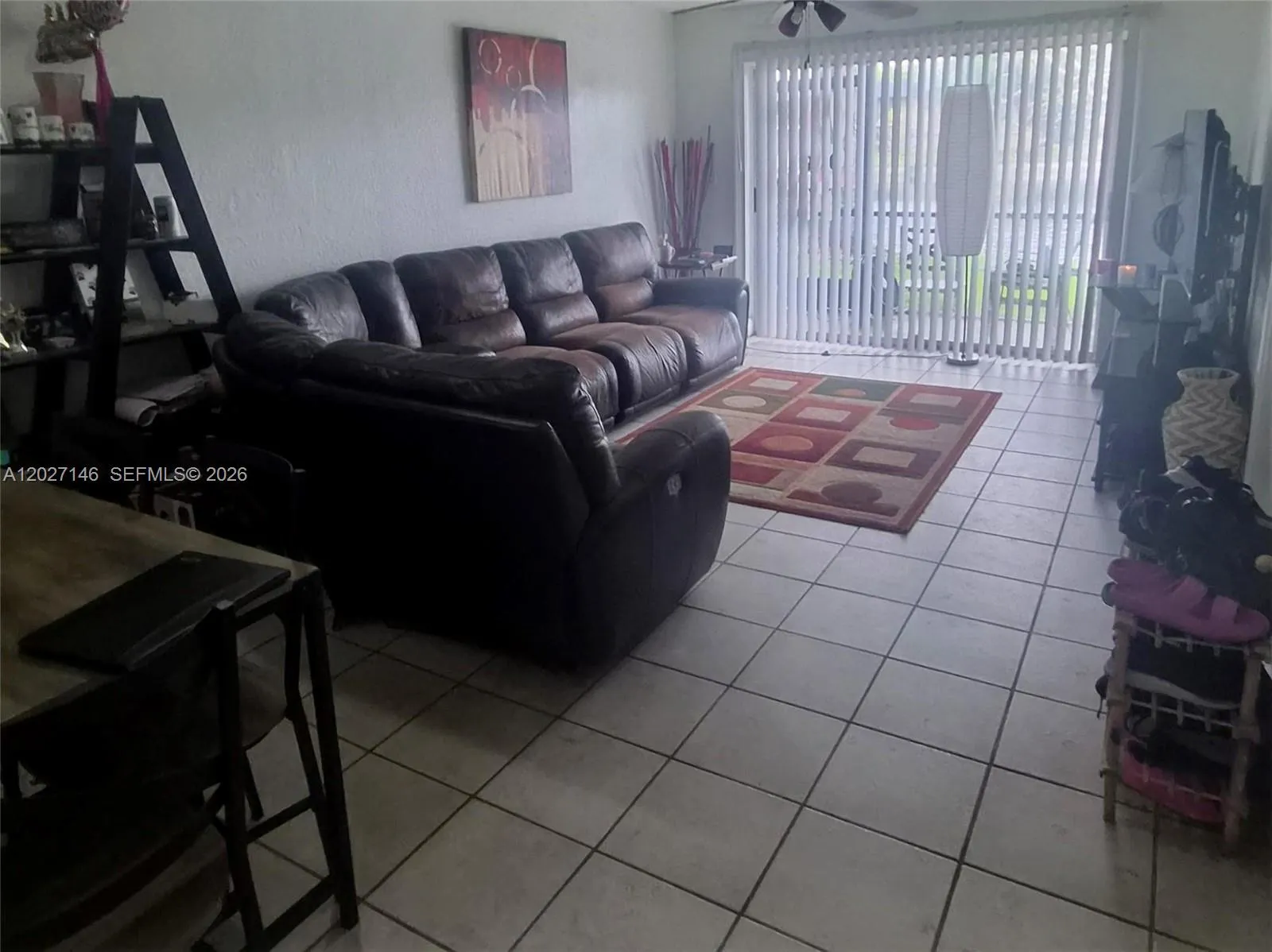 Light-filled, spacious living area featuring a large neutral tile layout, a comfortable sectional sofa setup, and massive sliding glass doors leading out to the patio.