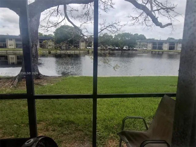 Relaxing screened-in porch framing a quiet, unobstructed view of the peaceful community lake and mature shade trees