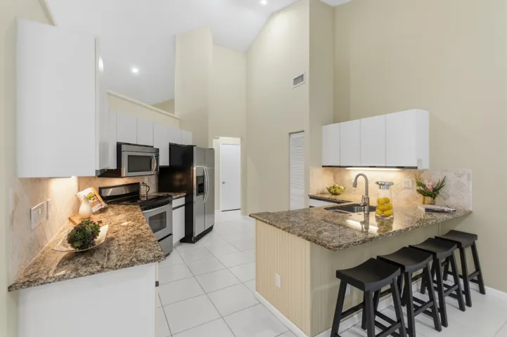 Kitchen with granite countertops, stone backsplash, stainless appliances, pantry and breakfast nook.
