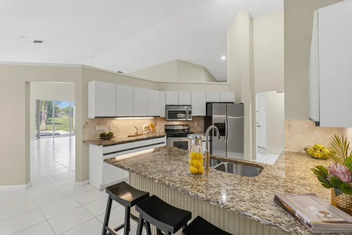 Kitchen with granite countertops, stone backsplash, stainless appliances, pantry and breakfast nook.