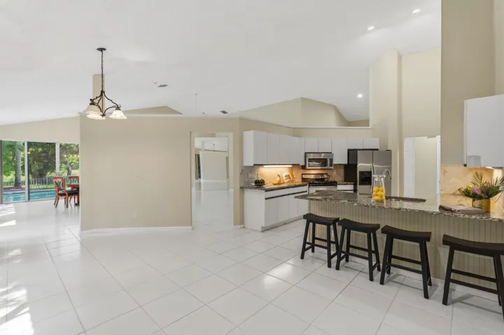 Kitchen with granite countertops, stone backsplash, stainless appliances, pantry and breakfast nook.