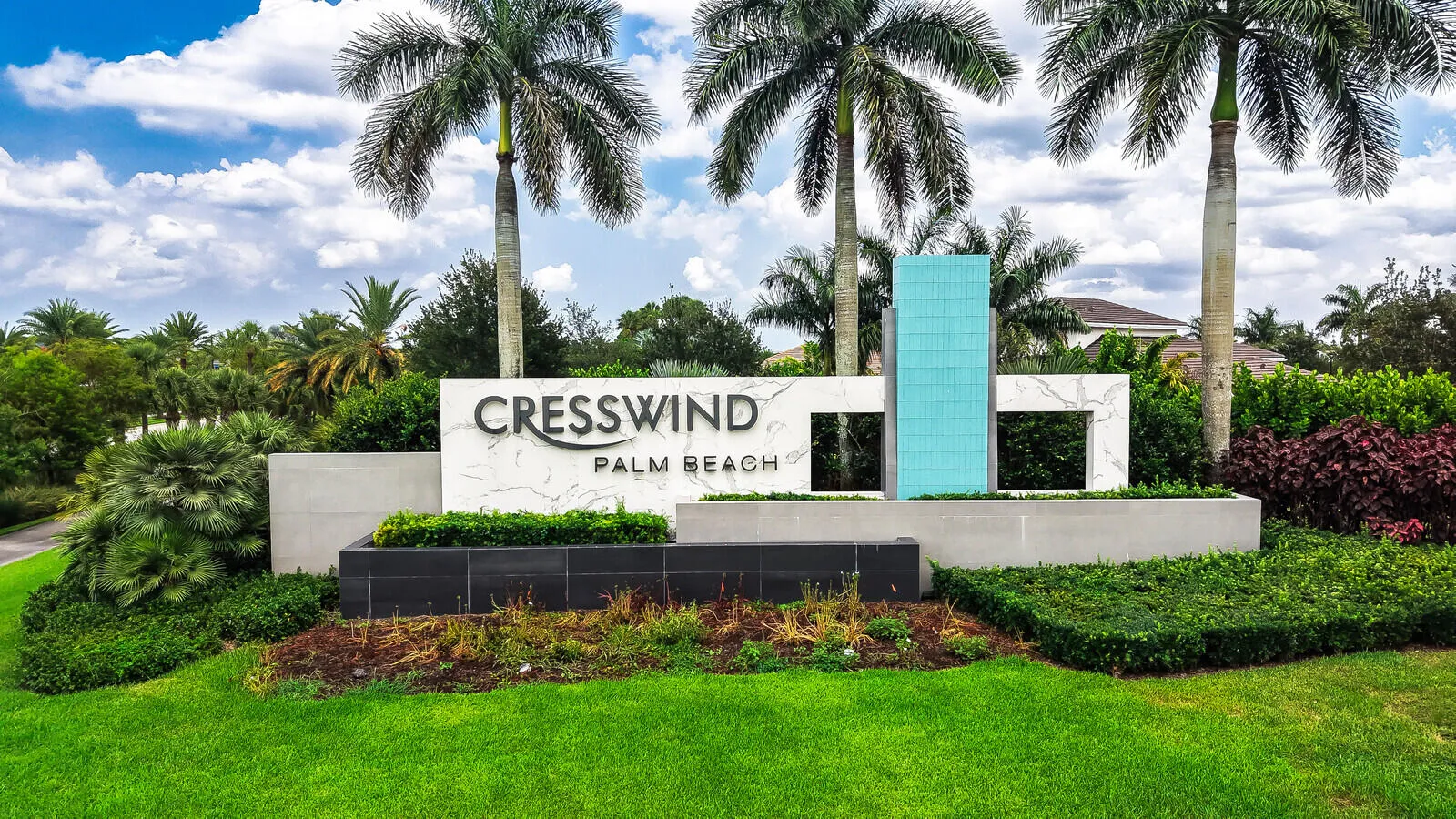 Community entrance signage featuring stone-look panels, embossed lettering, and a tiled accent column