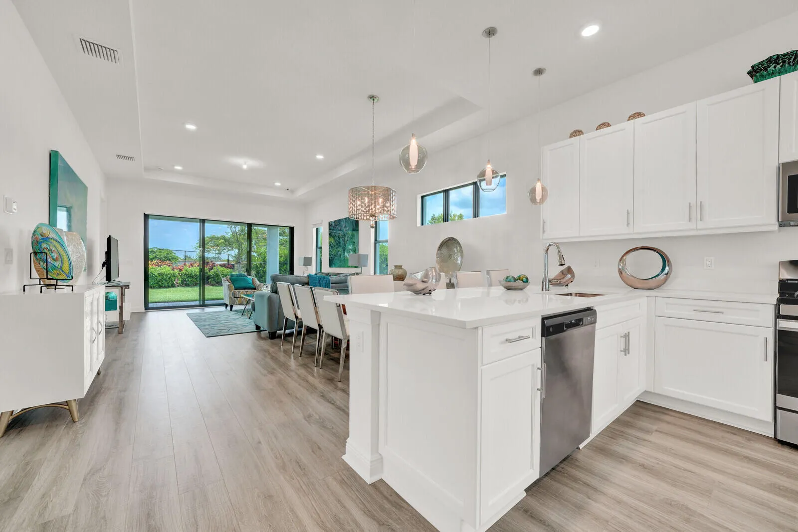 Open-concept living space featuring wood-finish flooring, a contemporary kitchen island with a white countertop, and a full suite of stainless steel appliances
