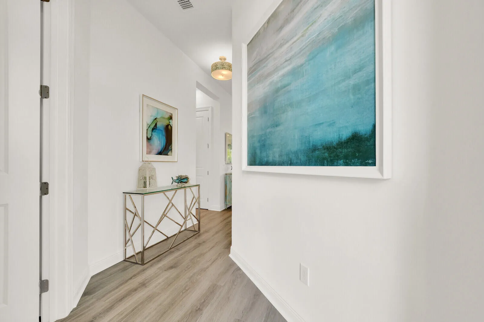 Hallway featuring light-toned wood-finish flooring, white baseboards, and bright white walls