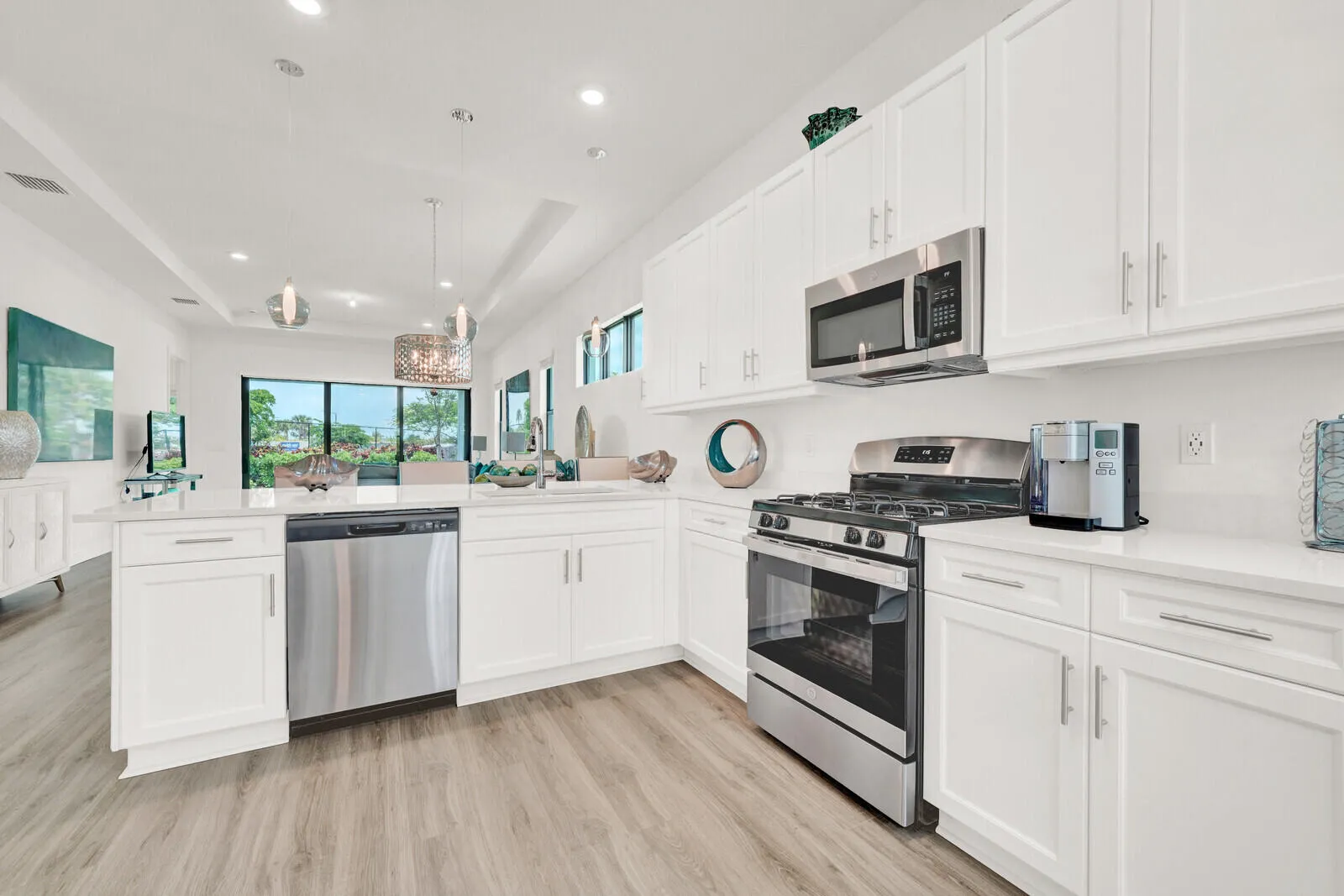 Open-concept kitchen featuring white cabinetry, stainless steel appliances, light-toned wood-finish flooring, and recessed lighting
