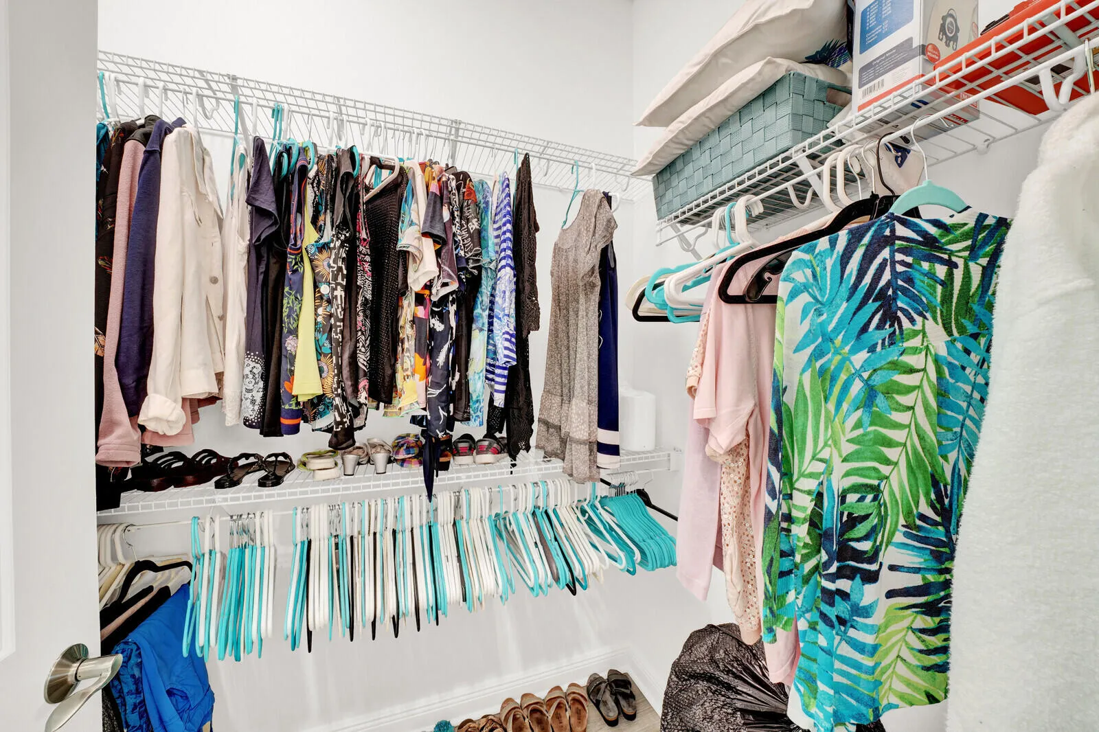 Walk-in closet featuring white wire shelving, multiple hanging rods, and ample storage capacity