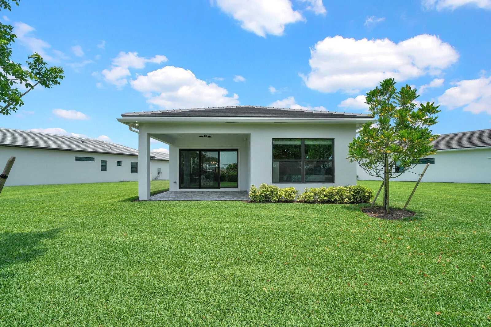 Expansive lawn area featuring a rear covered patio with recessed lighting, ceiling fan, and dark tile flooring