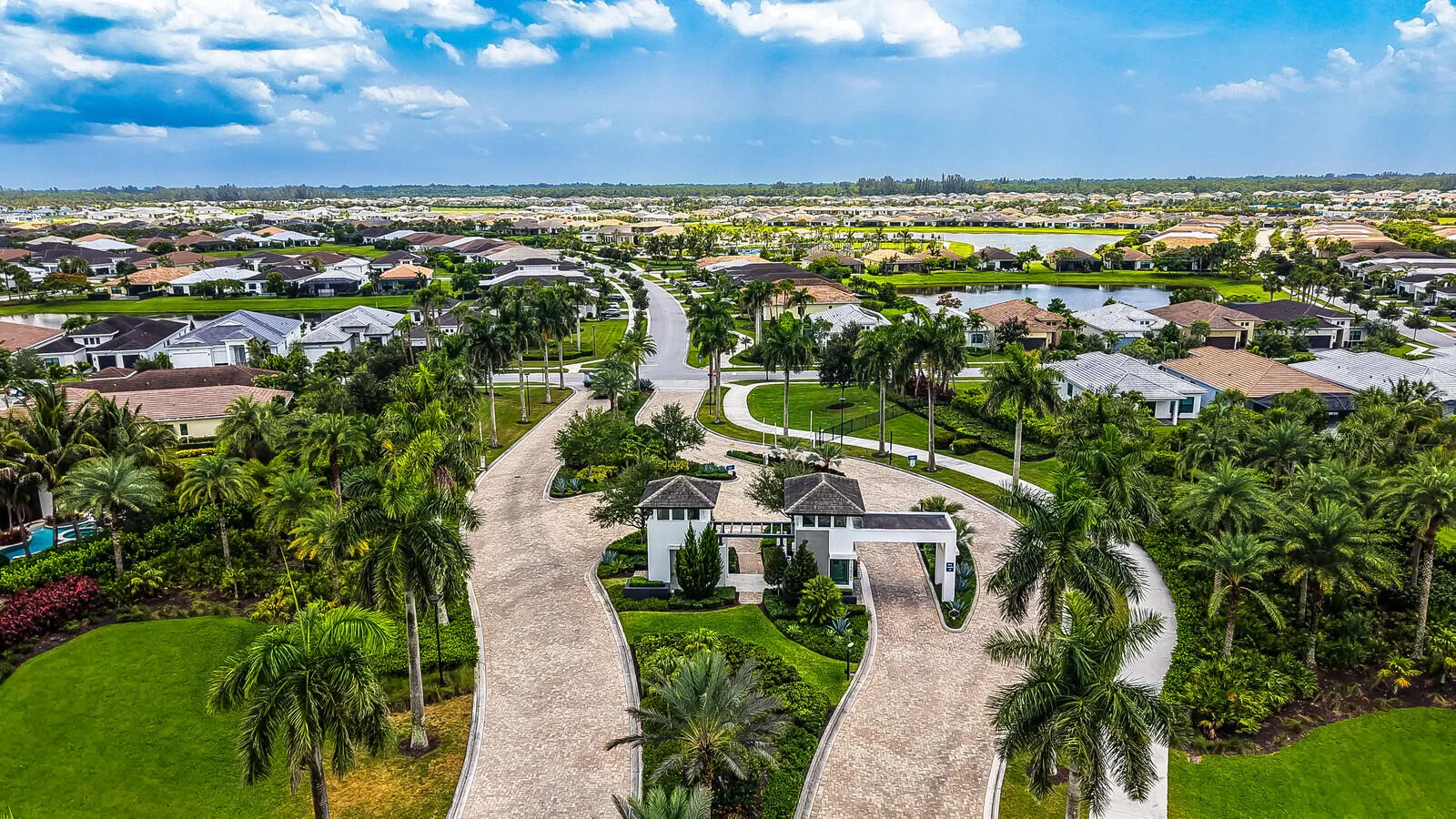 Aerial perspective showcasing the community entrance with mature palm trees and lush landscaping