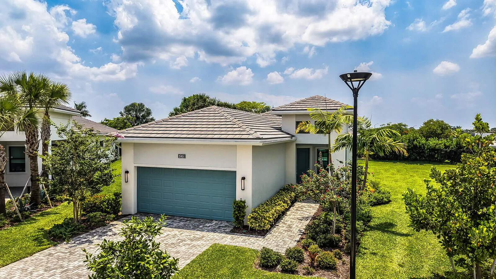 Modern single-story residence featuring a tile roof and a prominent teal garage door