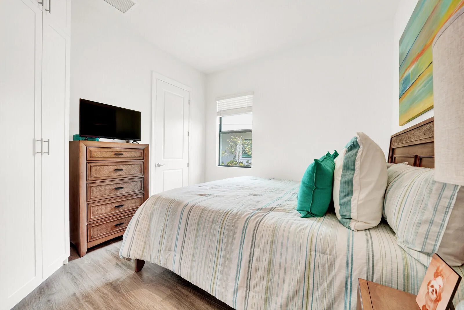 Room featuring wood-finish flooring, white walls, and a window with horizontal blinds
