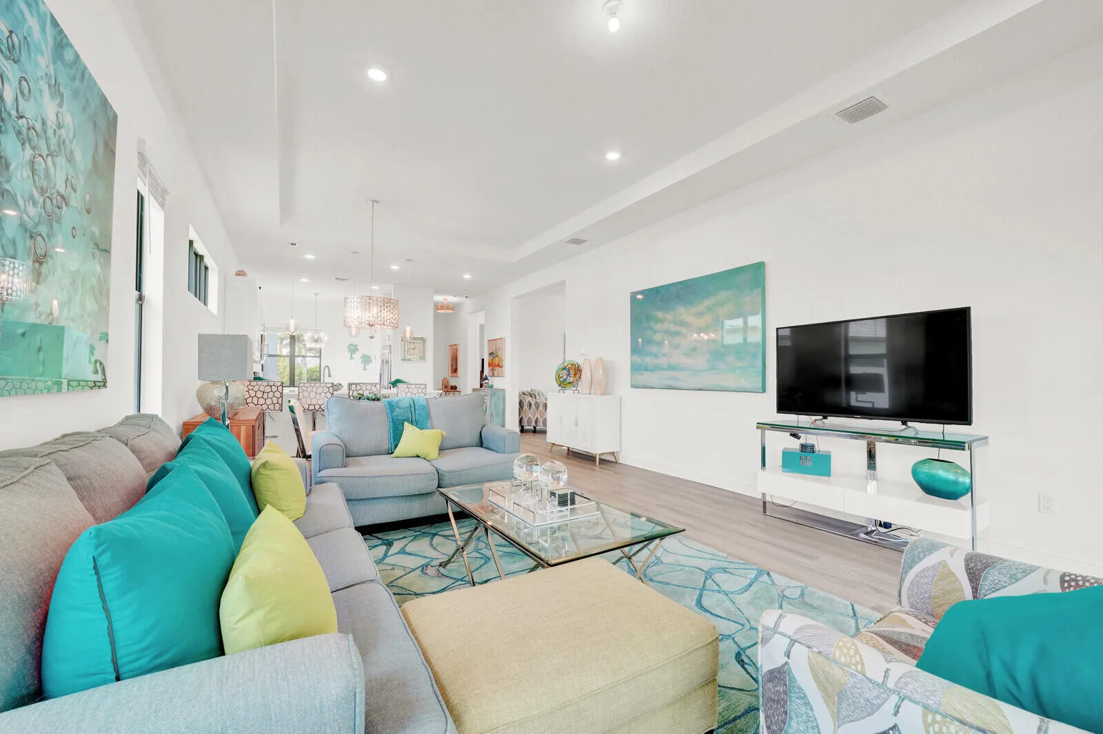 Expansive open-concept living area featuring wood-finish flooring, recessed lighting, and a tray ceiling