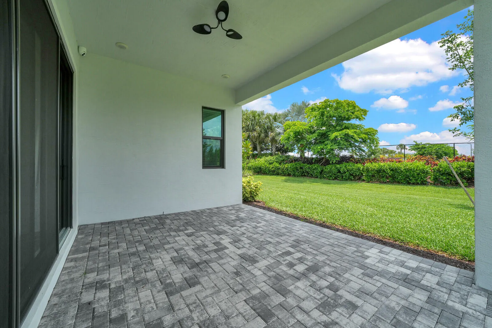 Expansive covered patio featuring patterned paver flooring, a ceiling-mounted fan, and recessed lighting