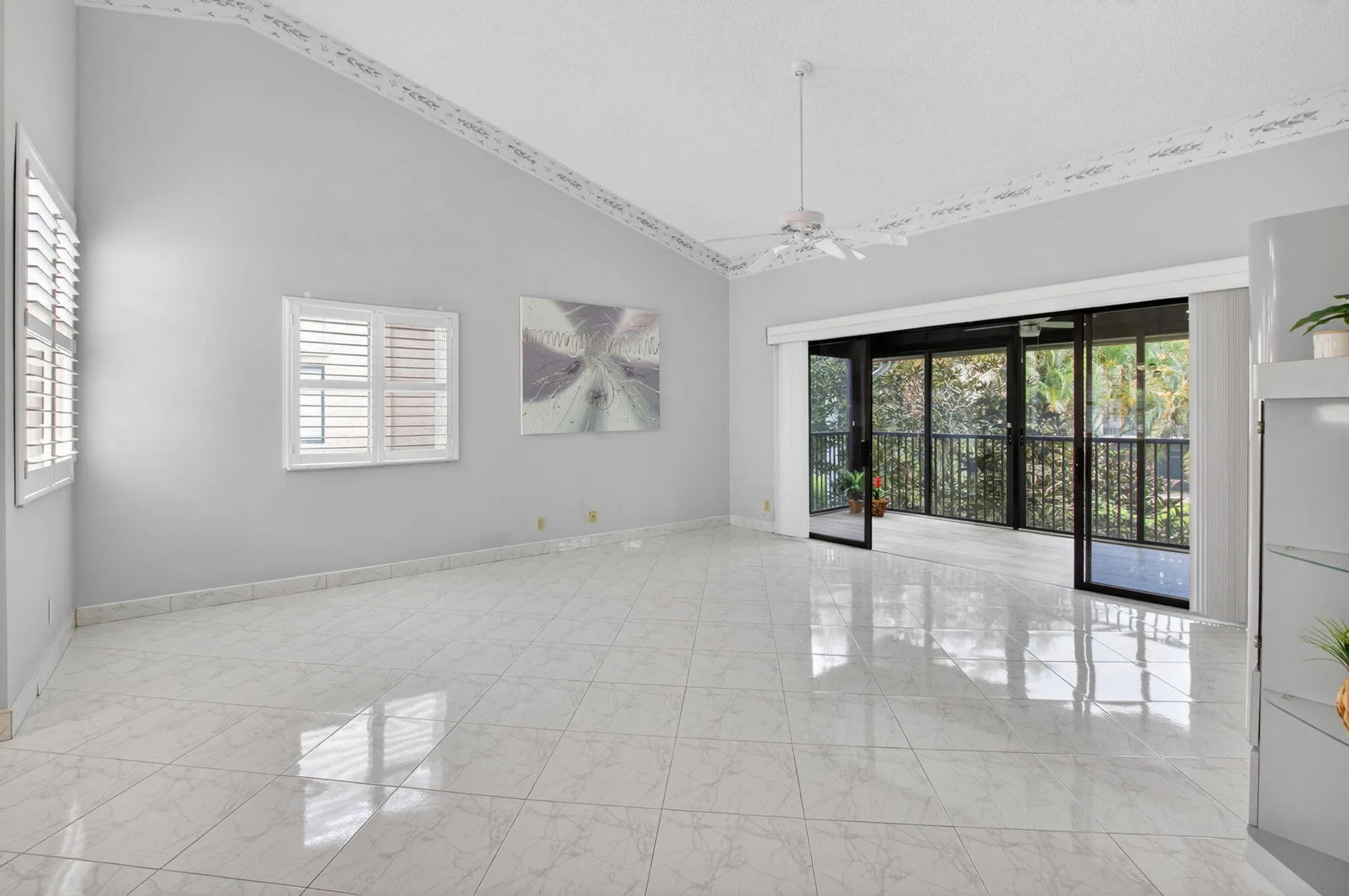 LIVING AREA OPENS TO THE ENCLOSED BALCONY WITH LOVELY GARDEN VIEW