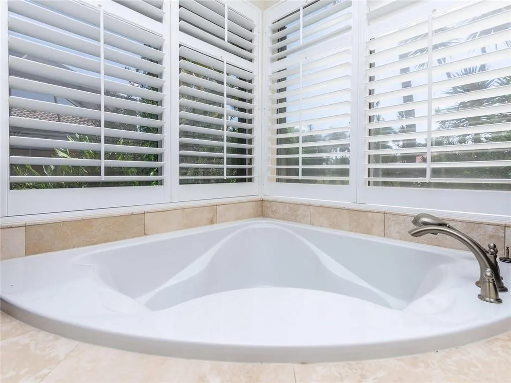 Oversized tub with Plantation shutters on double windows.