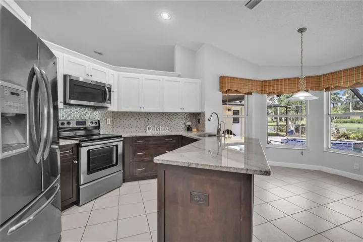 Remodeled kitchen with dual tone wood/white cabs, custom pullouts, stainless appliances, peninsula counter.