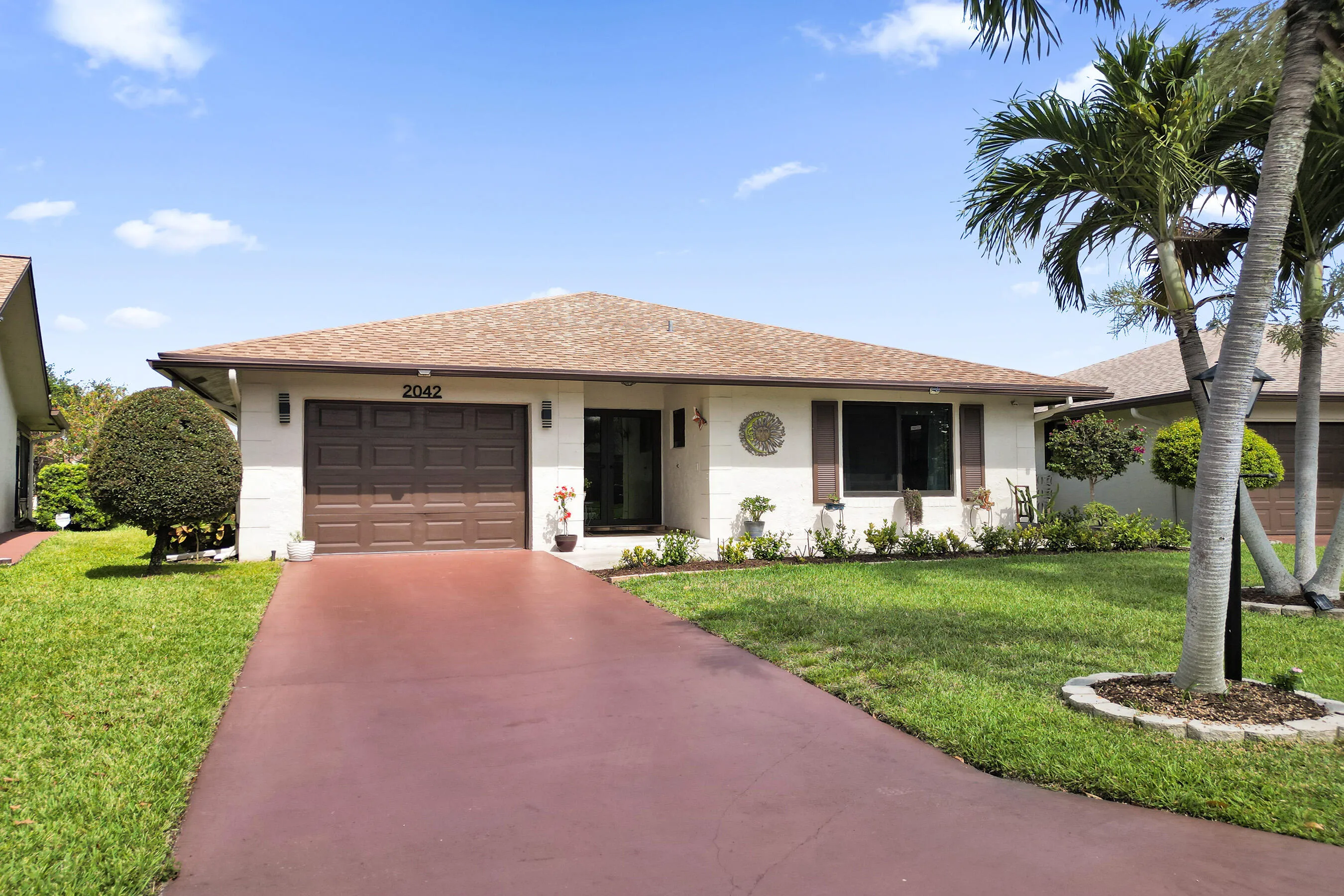 Front of home with long driveway and beautifully landscaped