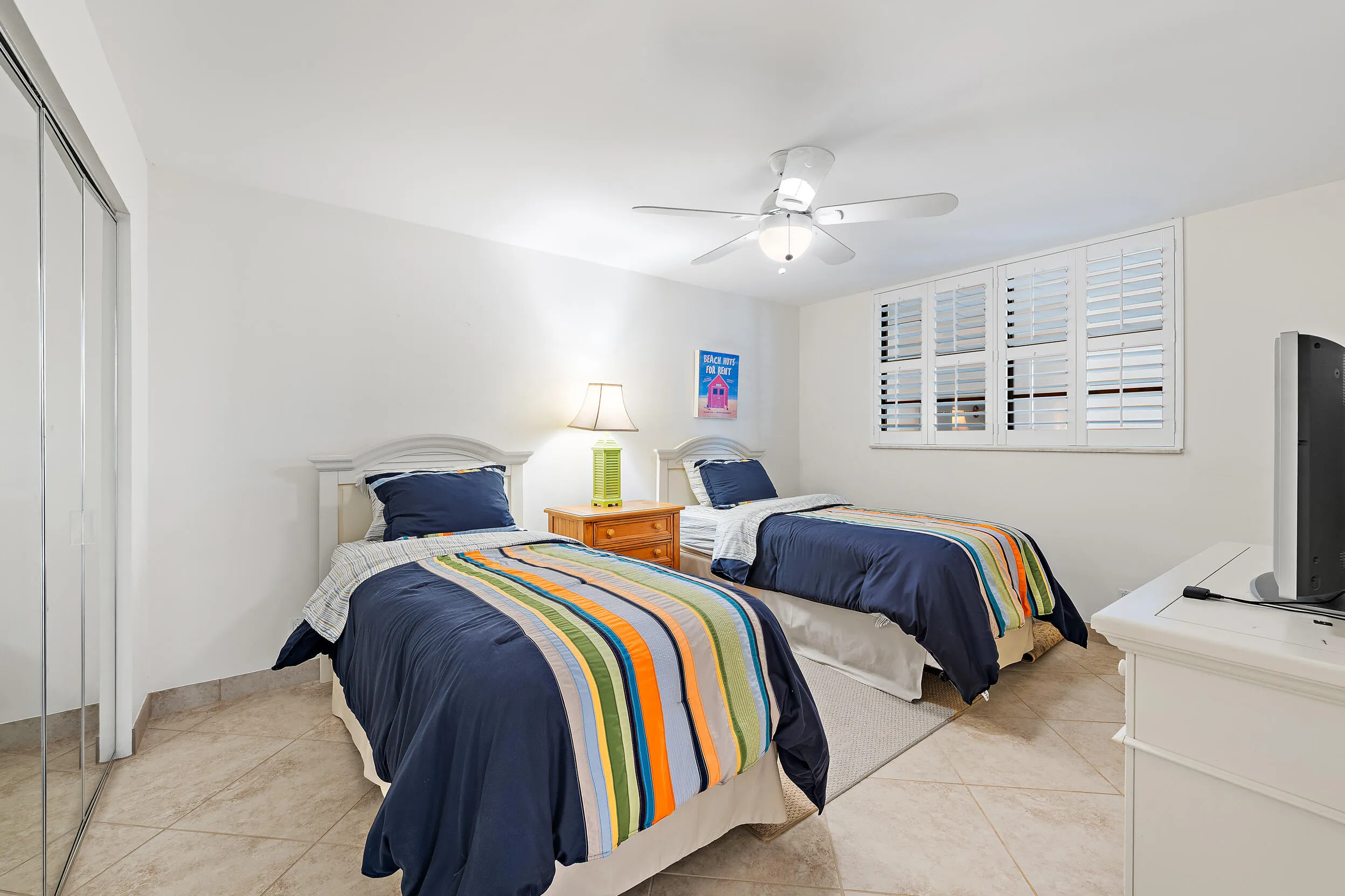 2nd bedroom with plantation shutters, tile flooring and closet space
