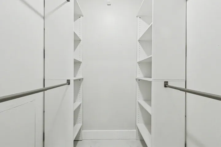 Primary closet with built in storage and a floor safe