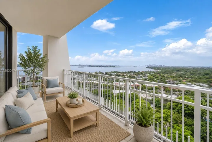 DIGITALLY STAGED BALCONY WITH VIEWS OF MIAMI WATERWAY AND LUSH GREEN SPACE.