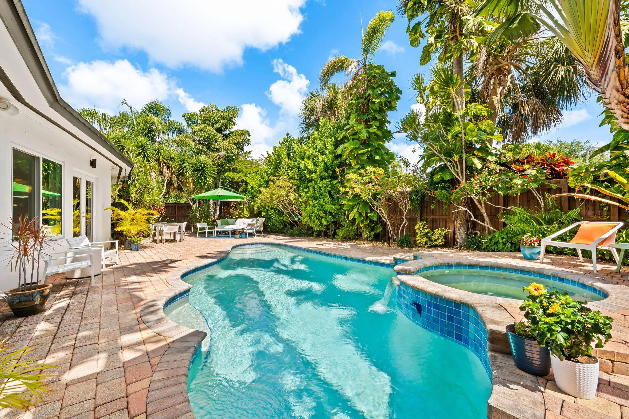 Tropically landscaped backyard photo of pool and spa.