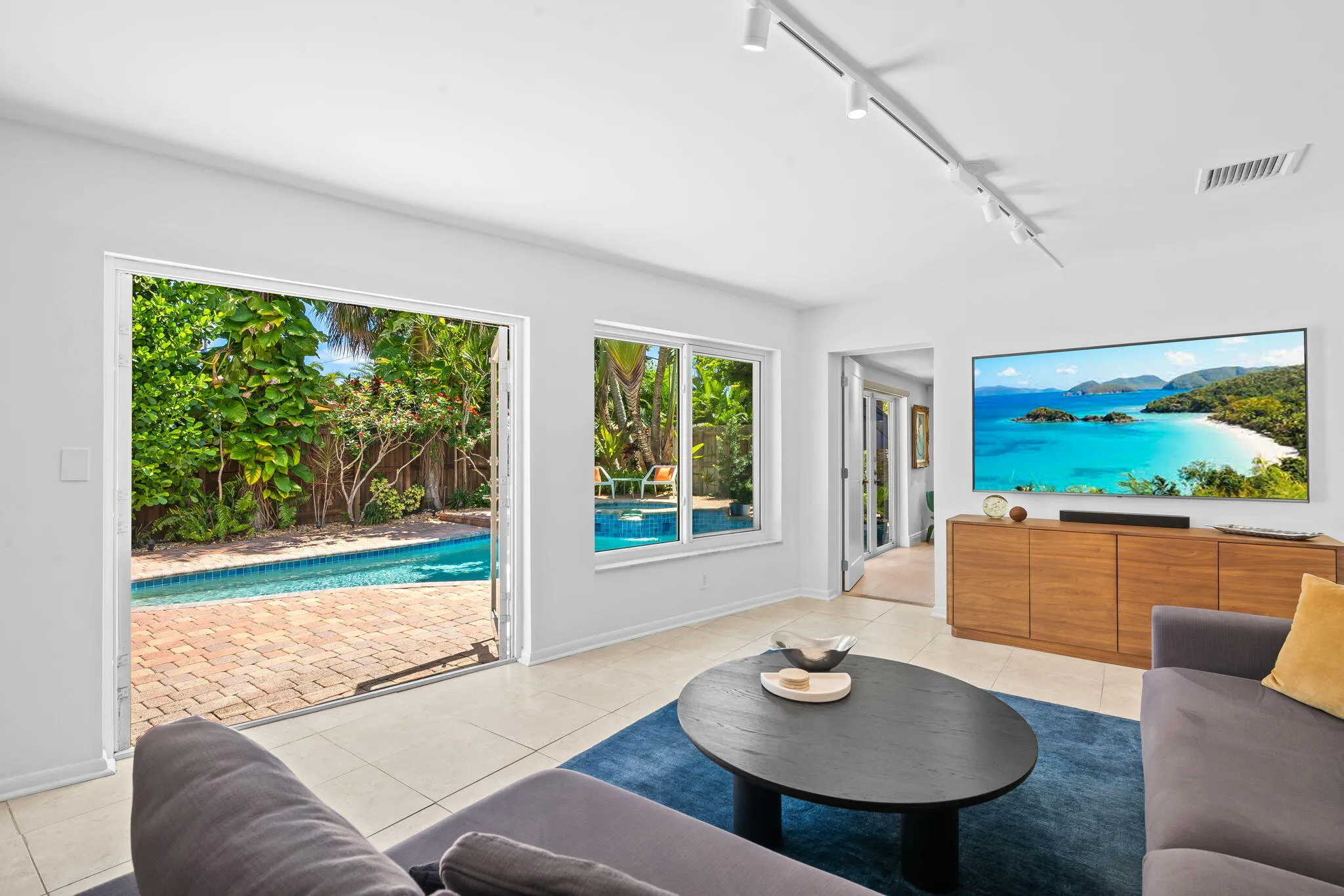 Family room with French doors open to the backyard pool area.