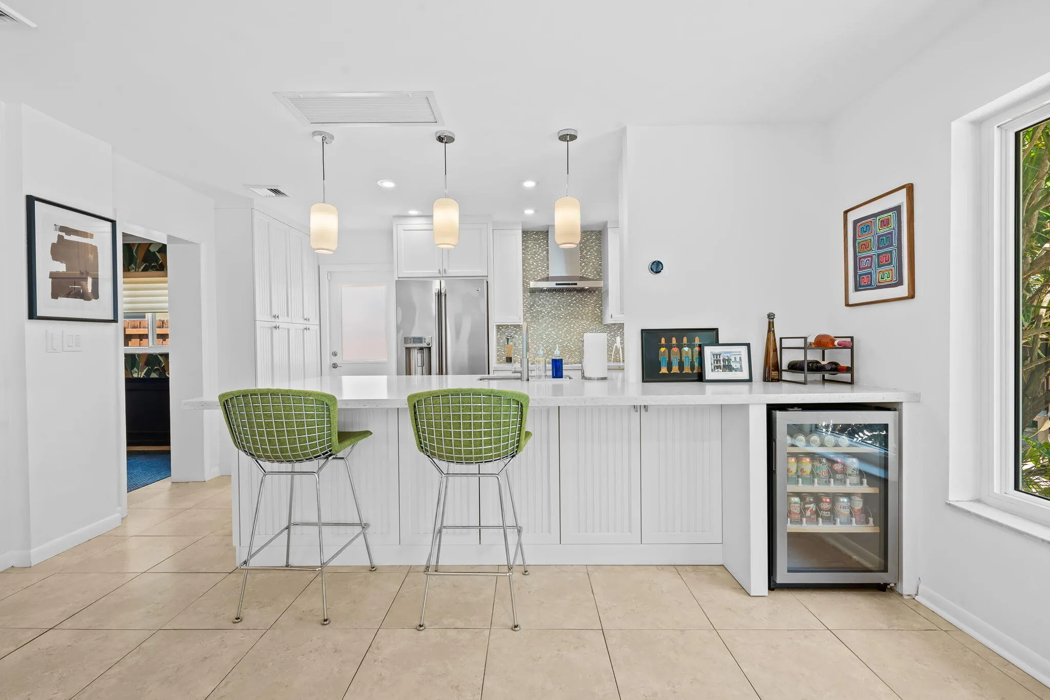 Kitchen with breakfast bar seating and wine cooler open to the family room.