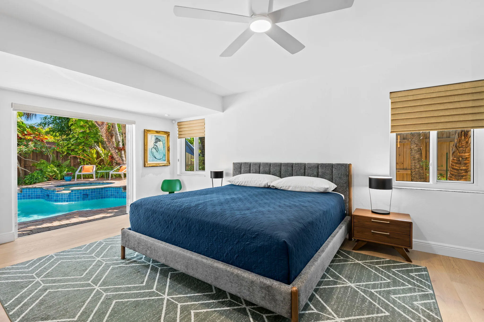 Primary bedroom with French doors open to the the backyard pool area.