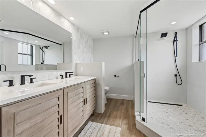 Primary bath with frameless shower, dual vanity and storage.