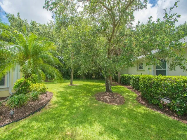 Expansive green lawn with mature trees and established perimeter hedging