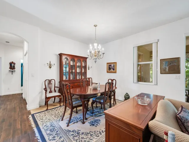 Formal dining area featuring a brass chandelier, crisp white walls, and a large window