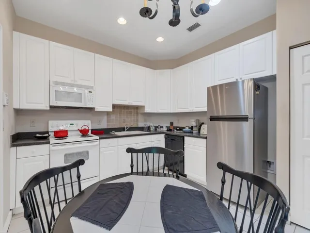 Kitchen featuring white cabinetry, dark countertops, a tile backsplash, and stainless steel appliances