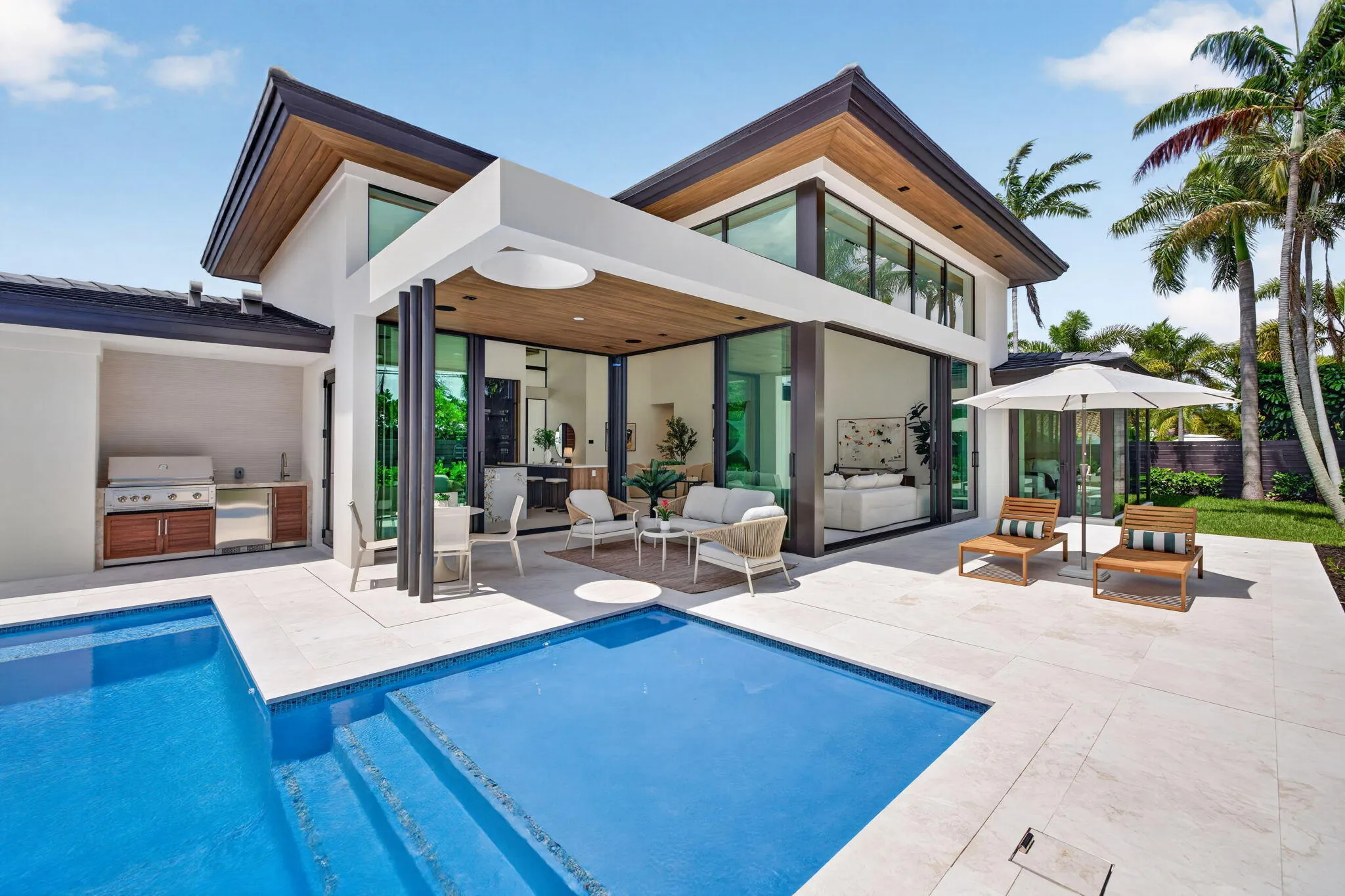 A resort-style patio setting connects the interiors to the pool, landscaping, and year-round open-air living.